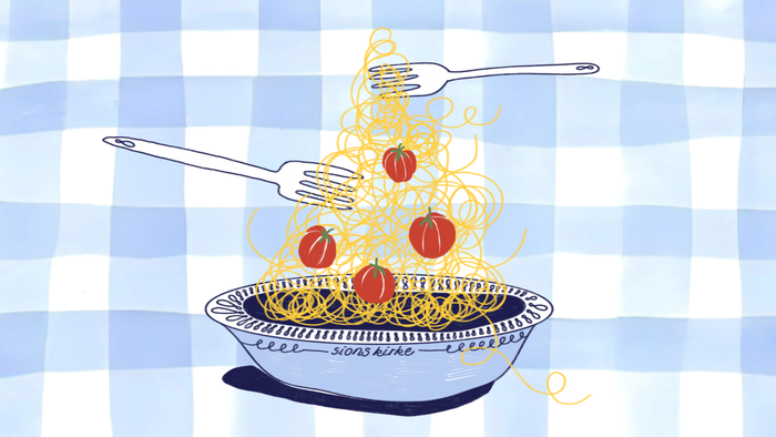 Lækkert spaghetti med cherrytomater, der løftes med en gaffel og kniv.