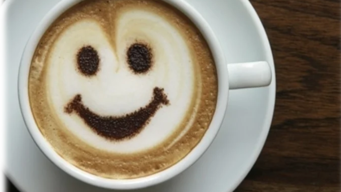 En kaffe med et smilende ansigt lavet af skum på overfladen.