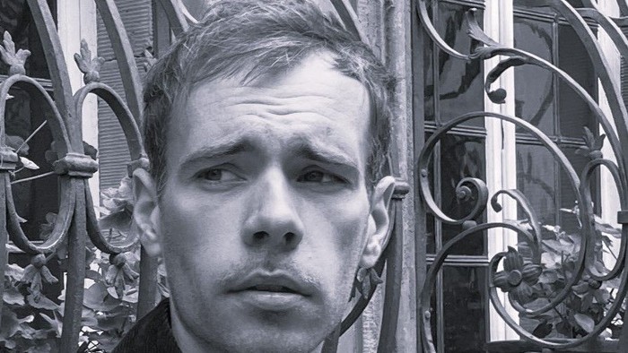 Mand i jakke står foran prægtig port.