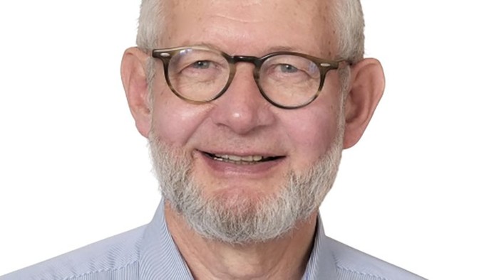 En ældre mand med briller og skæg, der smiler.