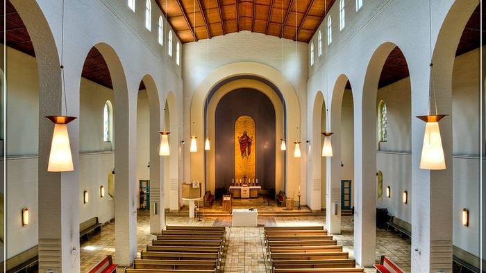 Große, helle Kirche mit hohen Bögen und Holzpulten