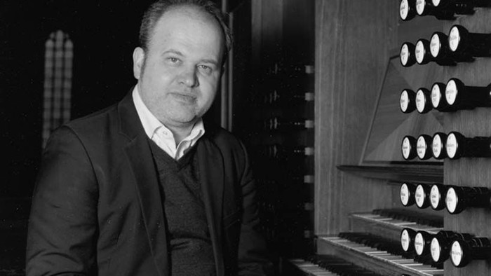 Mann in Anzug steht vor einem Orgelpfeifenregal