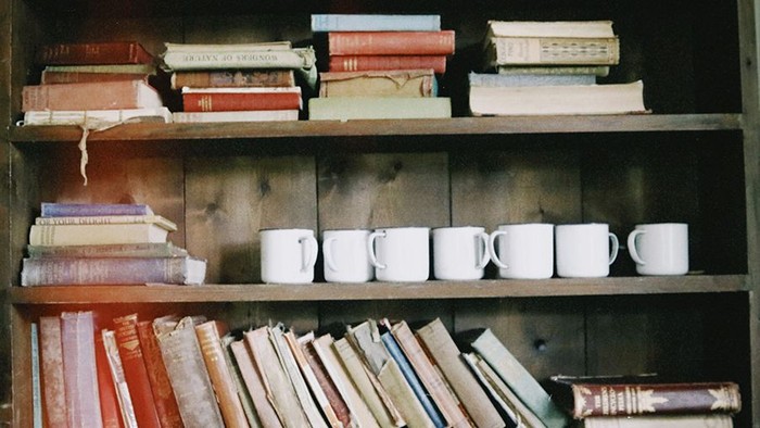 Bücher und Tassen arrangiert in Holzregal