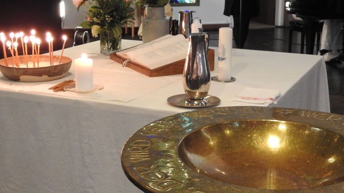 Kirchenaltar mit Kerzen, Blumen und Priester auf der Kanzel