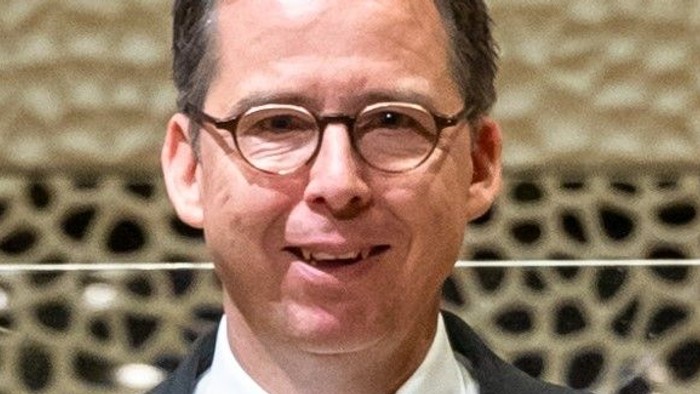 Mann mit Brille und Fliege posiert vor Mikrofon.