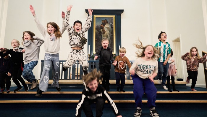 Børn danser og springer glade på scenen