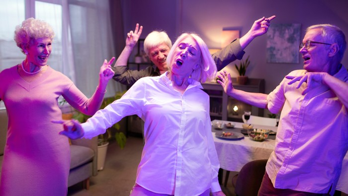 Eine Gruppe älterer Menschen tanzt ausgelassen in einem Raum