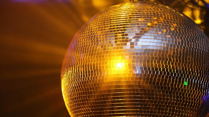 Eine Nahaufnahme einer glitzernden Discokugel, die lebendige, farbenfrohe Lichtmuster reflektiert.