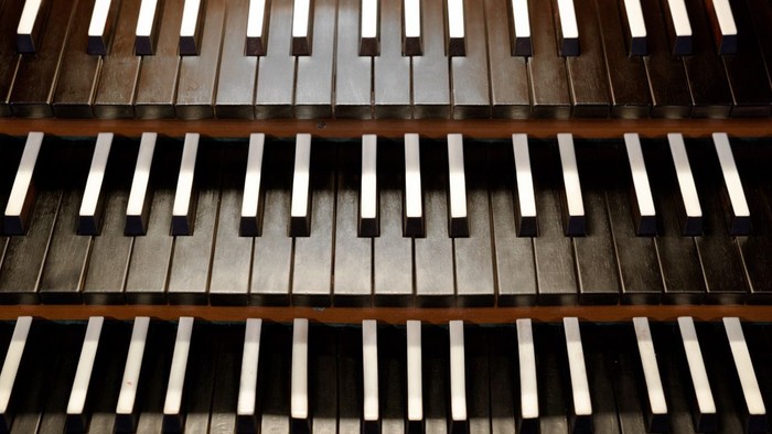 Nahaufnahme von drei Reihen Klaviertasten in kontrastierenden dunklen und hellen Farben.