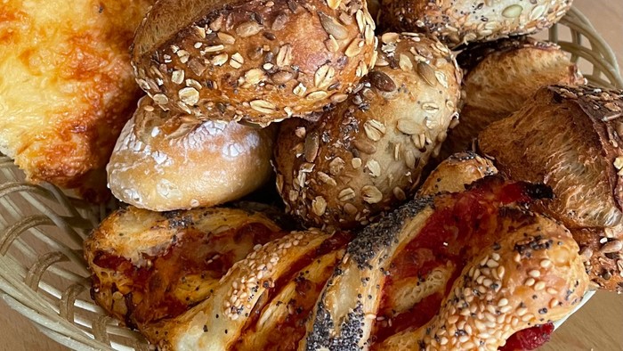 Ein Teller mit verschiedenen Brötchen und Broten, einige mit Sesam bestreut.