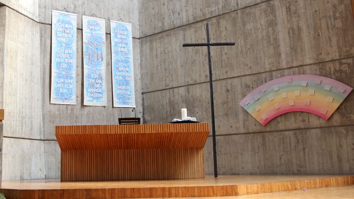 Die Kirche hat einen modernen Altar und ein farbiges Fenster.