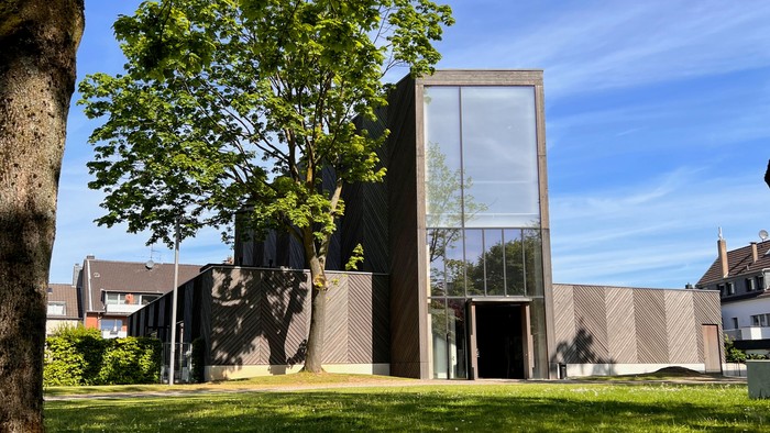 Modernes Gebäude mit großem Glasfenster und grünem Rasen im Vordergrund
