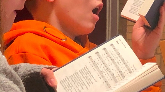 Børn i orangejakke læser bog