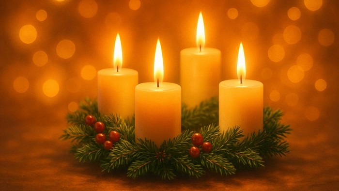 Adventskranz mit vier gelben, brennenden Kerzen