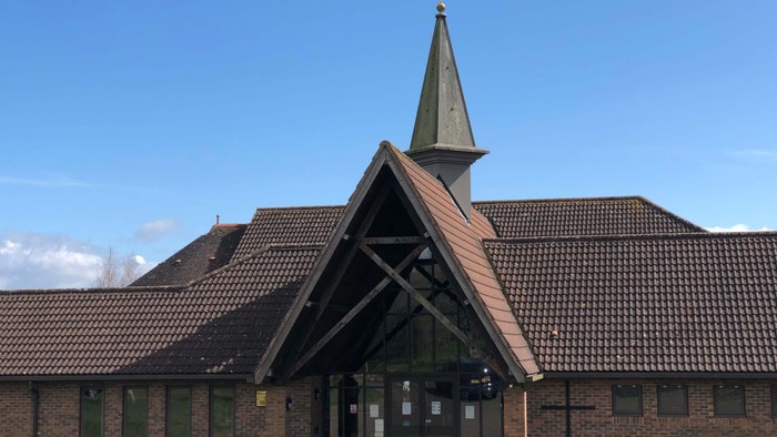 Church with tall steeple and brick exterior under blue sky