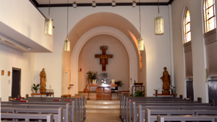 Die Kirche hat weiße Wände, Holzbänke und eine große Kreuzigungsszene im Altarbereich