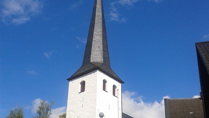 Weiße Kirche mit hohem Turm und blauen Himmel
