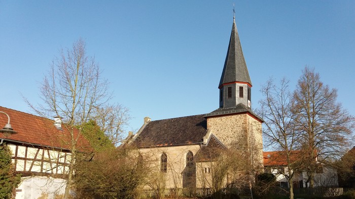 Kirche mit hohem Kirchturm und umgebenden Bäumen.
