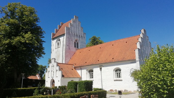 Et hvidt kirkebygning med røde tag og en tårn med spidser.