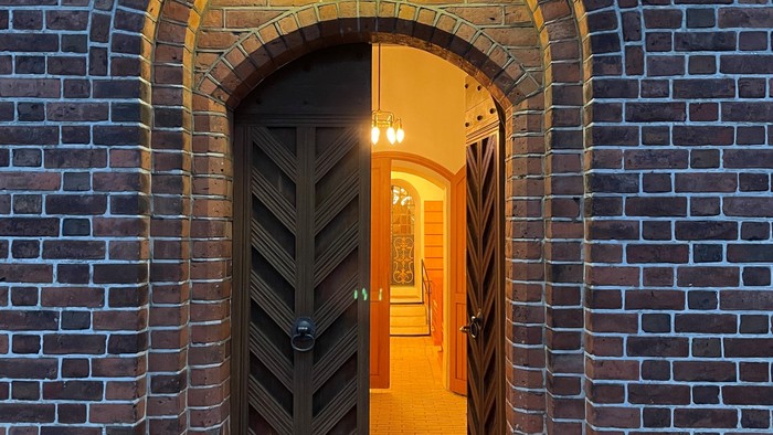 En mørk trædør i mursten med lys over og på hver side