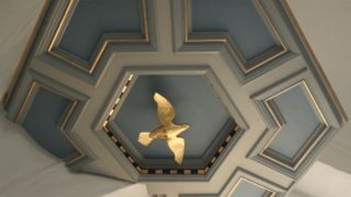 En blå og guld farvet dekoration med et guld fjer i midten