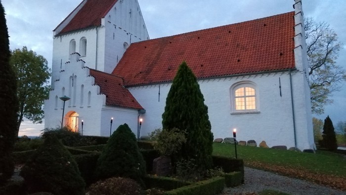 Et hvidt kirkebygning med røde tag og en smuk have foran