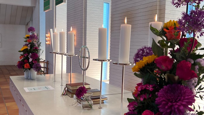 Farverige blomster og lys på alter i kirke