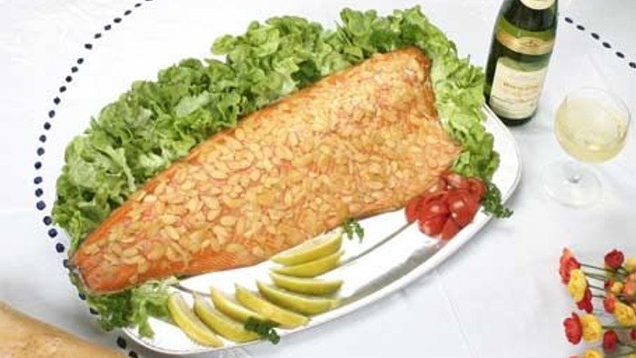 En ret med stekt fisk, grønsalat og citronstykker på en hvid plate.