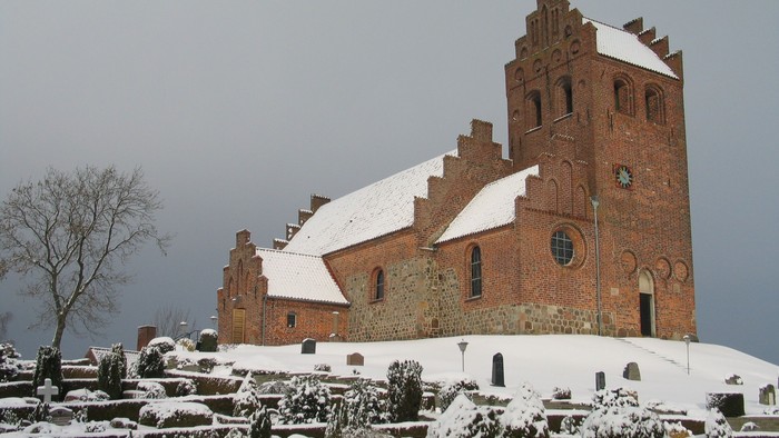 En snede kirke med tårn og gravsteder.