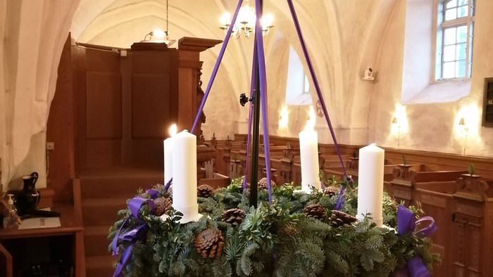 Indre del af kirke med adventkrans og lys.