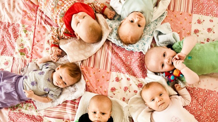 Børn og tøjser ligger på en rosa patchworkede blåsen