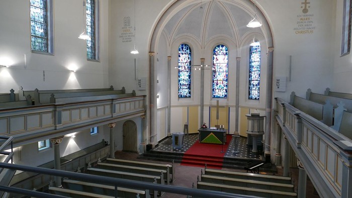 Die Kirche mit hohen Decken, Kirchenbänken und bunten Glasfenstern.