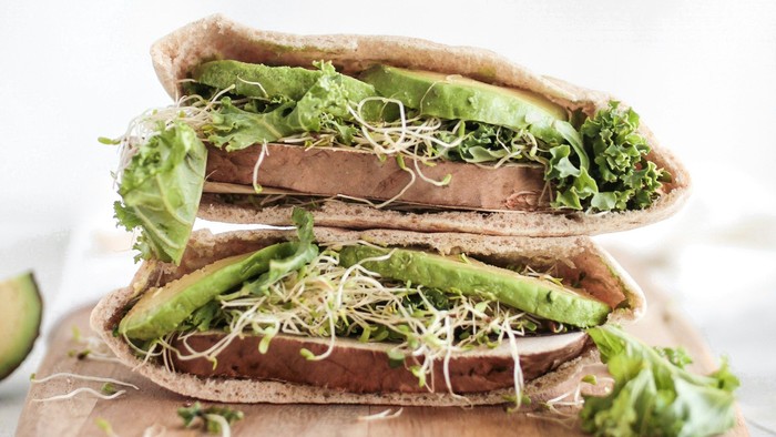 En sandwich med grønne ingredienser på brød og skåret i to.