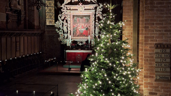 Juletræ i en kirke med lys og religiøs kunst