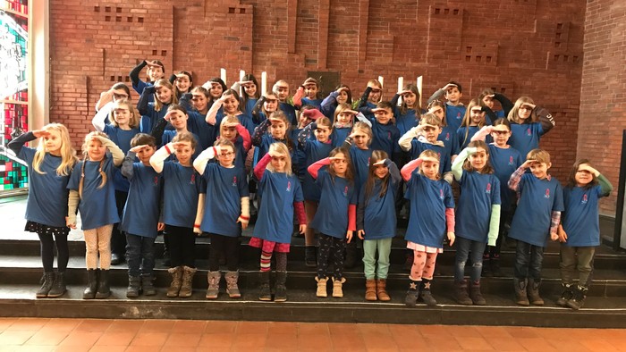 Gruppe von Kindern in blauen Uniformen vor Backsteinmauer