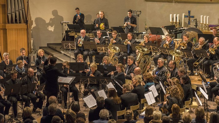 Ein Orchester spielt in einem großen Saal vor einem Publikum.