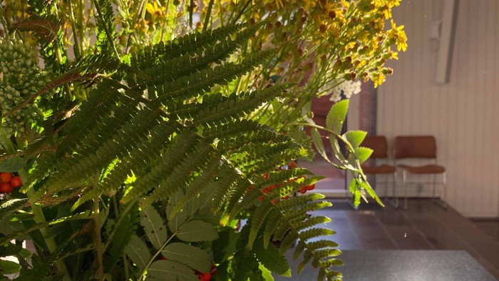 En stor blomsteraarrangering i et blå vase på bord.