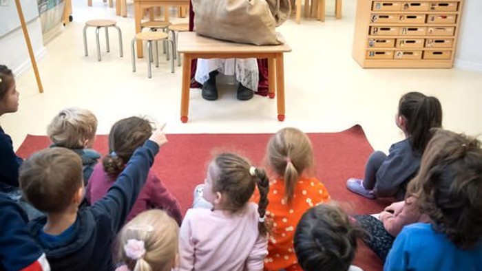 Kinder sitzen im Kreis um einen Tisch mit Puppen.
