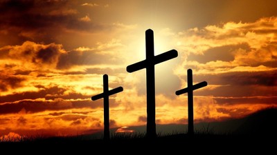 Tre kors stiger op mod en dramatisk solnedgangshimmel.