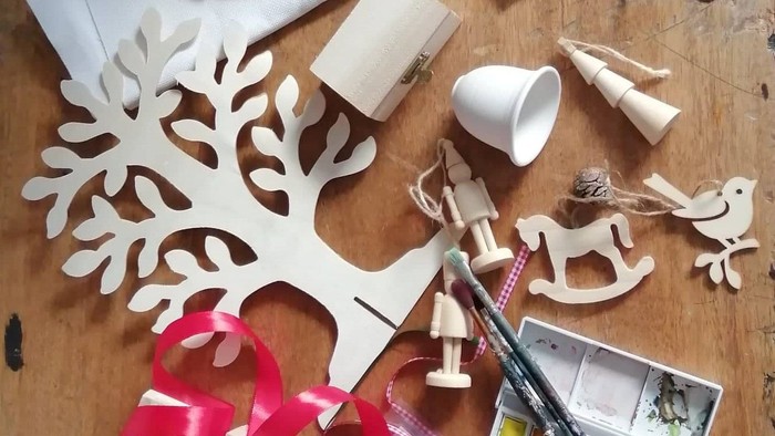 Billedet viser forskellige håndværksmaterialer og dekorationer, herunder skærm, malerfarver, og juleornamenter.
