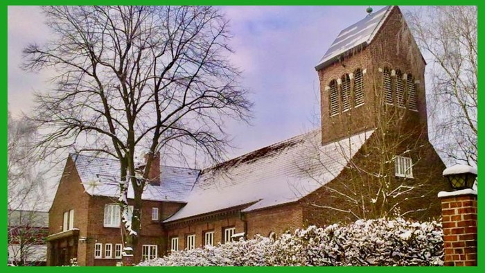 Ein schneebedecktes Ziegelgebäude mit einem hohen Turm und kahlen Bäumen im Winter