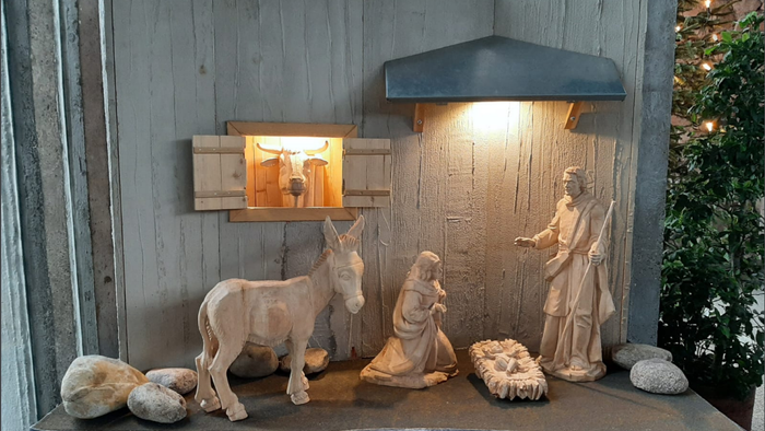 Eine Krippe mit Holzfiguren vor einer Holzwand