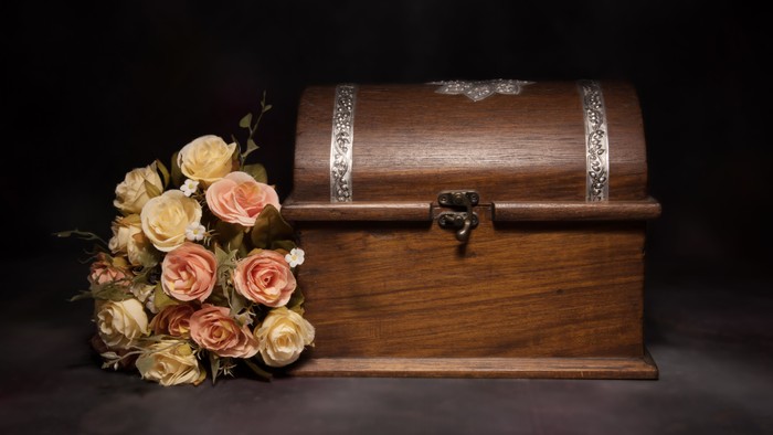 Small brown casket next to some roses.