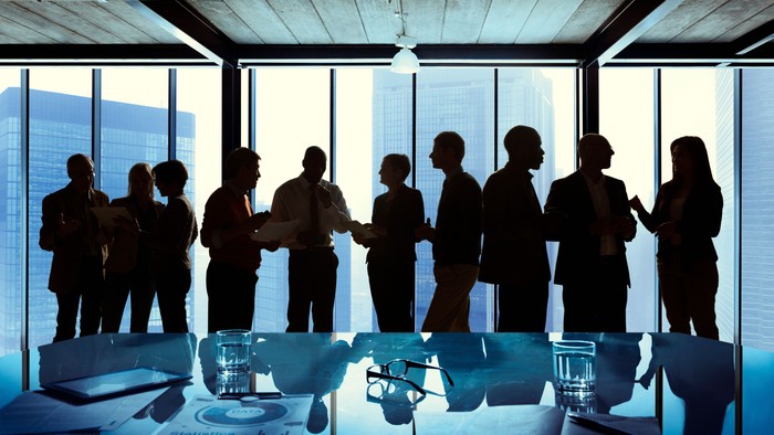 silhouettes of people talking next to a boardroom table 