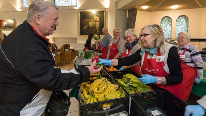 Eine Gruppe von Menschen verteilt Lebensmittel, darunter Bananen, in einer Kirche.