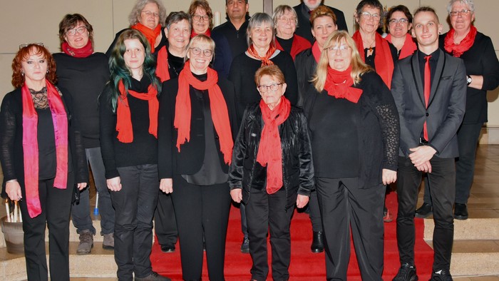 Eine Gruppe von Menschen posiert für ein Foto, alle tragen schwarze Kleidung und rote Schals