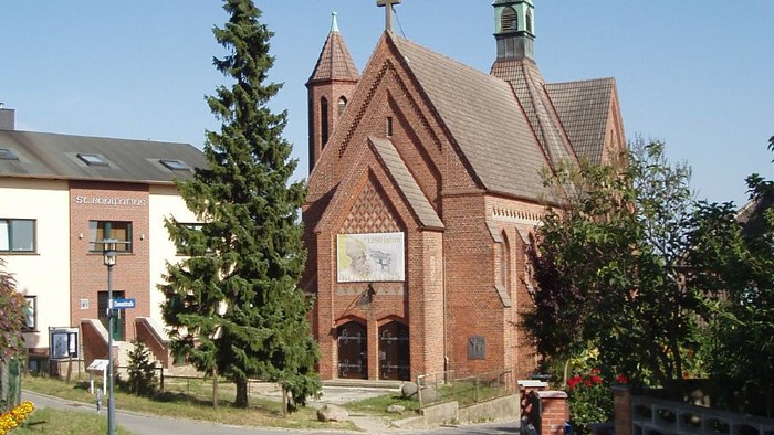 Kirchengelände mit Kopfsteinpflasterweg und Bäumen