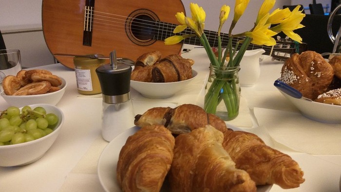 Frühstückstisch mit Croissants, Obst und Blumen