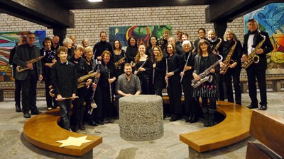 Eine vielfältige Gruppe von Saxophonist:innen posiert gemeinsam in einem farbenfrohen, künstlerischen Innenraum.