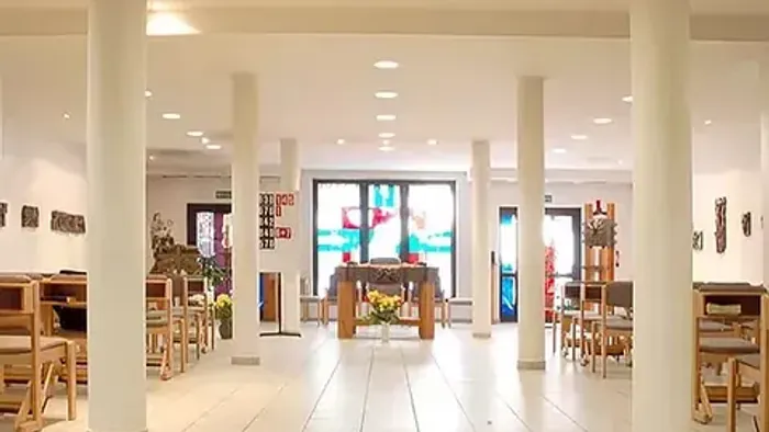 Modernes Café mit hohen Säulen und hellen Farben, Holzstühle und Tische, große Fensterfront